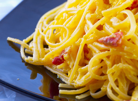 Pasta alla carbonara in close up, over black reflecting plateの写真素材