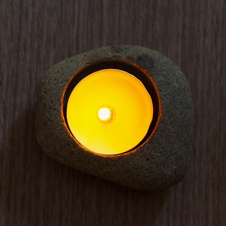 Candle in stone for decoration, over wooden tableの写真素材