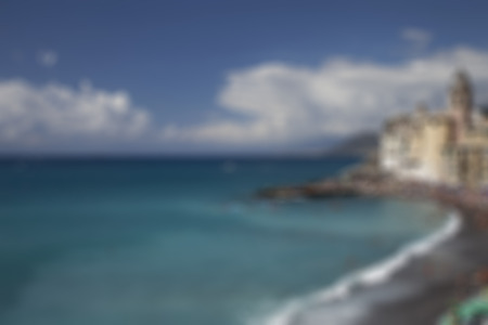 Blurred background: wonderful blue sea and beach intentionally defocused, with big clouds and small town on the right, horizontal imageの写真素材