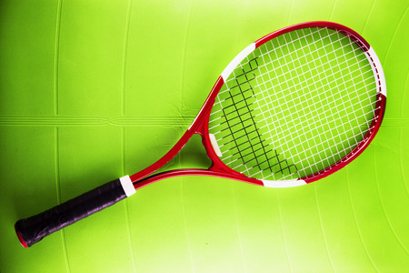Tennis racket over green synthetic surfaceの写真素材