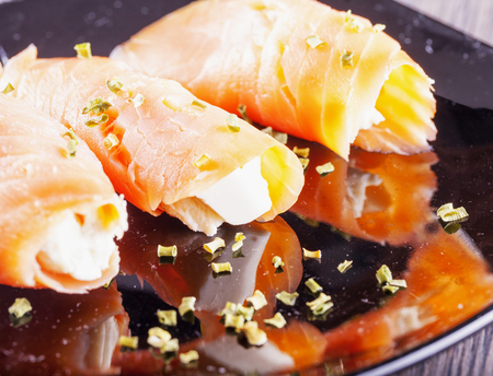 Salmon with cheese, over black reflecting plate, horizontal imageの写真素材