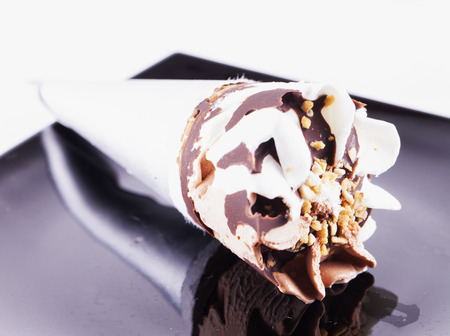 Ice Cream with chocolate and cream over black plate, horizontal imageの写真素材