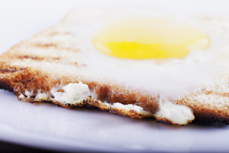 Egg in a hole over white plate, focus over first border, horizontal imageの写真素材