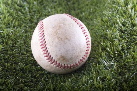 Old Baseball in closeup over synthetic grass, horizontal image