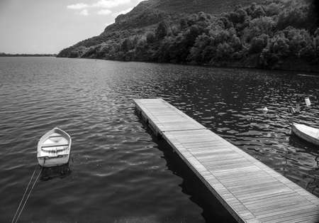 Pier with bounded boat over black and white landscape
