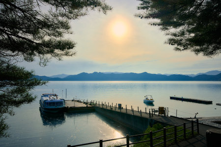 Sunset on the lake with boats and mountains in the background.の写真素材