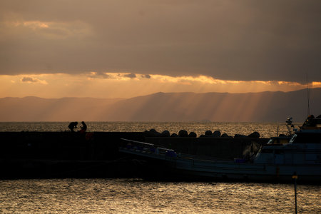 Sunset at the sea with boats and rays of the sun.の写真素材