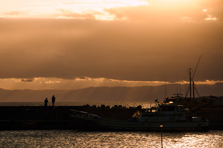 Silhouette of a fishing boat in the harbor at sunset.の写真素材