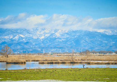 A man walks along the shore of a lake.の写真素材