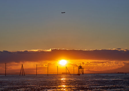 Sunset over the sea with the silhouette of a lighthouse in the foregroundの写真素材