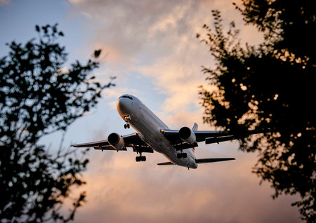 Airplane flying in the sky at sunset. Side view of a passenger plane taking offの写真素材