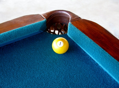 Pool ball with number 1 near the hole of the table