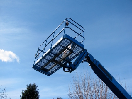 Boom lift reaching high up. Blue elevated work bucket platform, articulating bending arm.