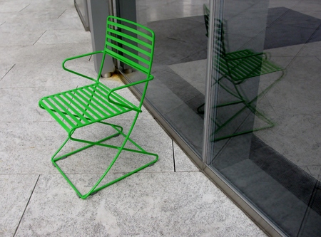 Green metal chair and glass wallの写真素材
