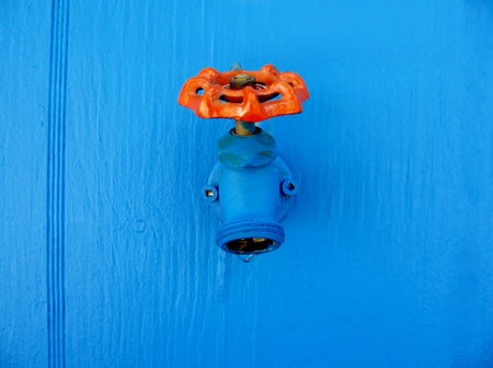 Closeup faucet on blue wall background. Tap closeup with dripping water-drop.の写真素材