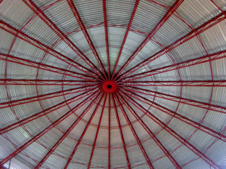 Ceiling of industrial hangar or warehouse. High ceiling, red metal construction.