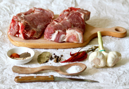Raw meat on a wooden cutting board with spices and garlicの素材