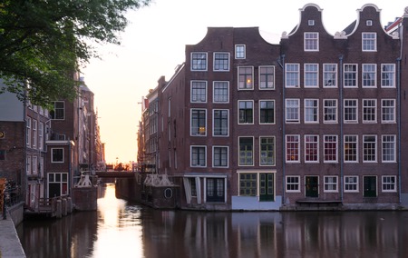 Sunset reflected in the water of the Amsterdam canal against the background of beautiful houses.の写真素材