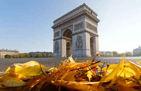 The famous Triumphal Arch and autumnal colorful leaves in the foreground at sunny day , Paris, France.の写真素材