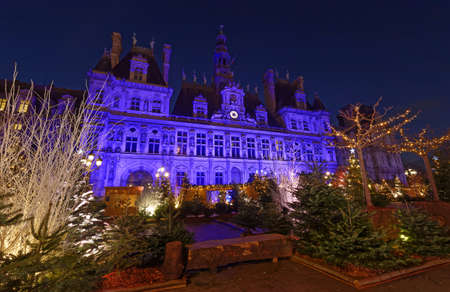 Parisian City Hall decorated with Christmas trees for winter holidays at night. Winter travel and tourist attractions in Europe concept. Celebration background.の写真素材