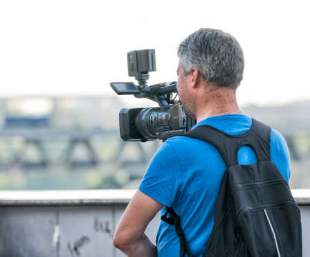 Videographer with a backpack on a field removes shootingの写真素材