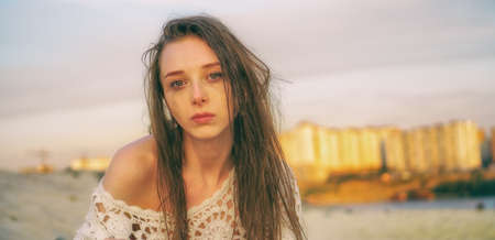 Beautiful girl crying at sunset against city backgroundの写真素材