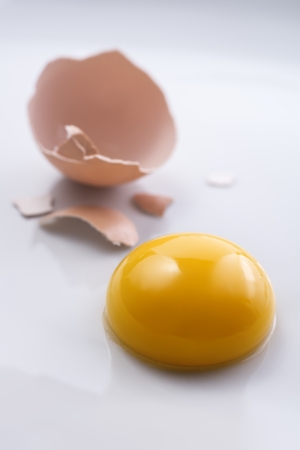 Broken egg and yolk on white backgroundの写真素材