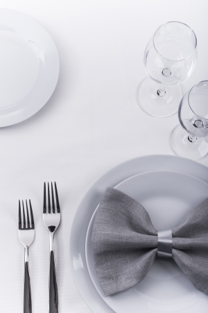 Plates and silverware with grey napkin on white tableclothの写真素材
