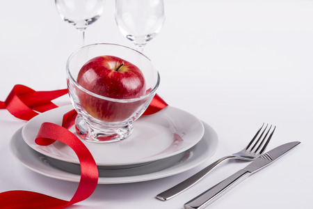 Red apple in glass bowl and two plates on white background for menuの写真素材