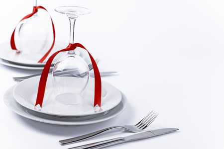 Wine glasses turned upside down with red decoration as background for invitation and menuの写真素材