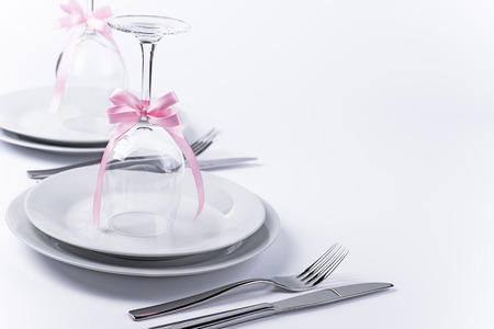 Wine glasses turned upside down with pink decoration as background for invitation and menuの写真素材