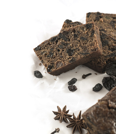 Christmas fruit sponge cake pieces with spices on white paperの写真素材
