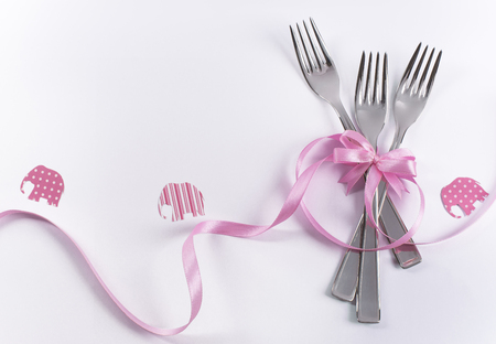 Silverware on white with pink ribbon as background for menu and invitation