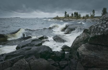 Close-up of waves of stormy sea break on rocky shore. Horizontal layout for travel materialsの写真素材
