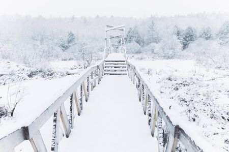 Wooden bridge under snow. Winter time. Wide angle image for travel and adventure stories