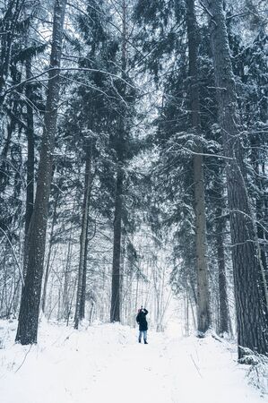 Travel photographer takes pictures in snow forest. Vertical layoutの写真素材