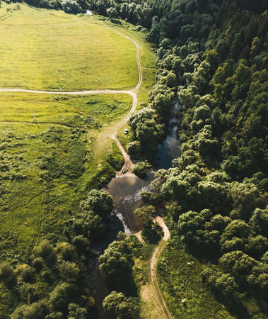Small river between the field and the forest. Aerial view. Vertical layout. Drone photographyの写真素材
