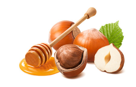 Hazelnuts in nutshell and honey dipper isolated on white background. Package design element with clipping pathの写真素材