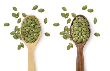 Two wooden spoons with green pumpkin seeds isolated on white background. Light and dark wood. package design elements with clipping pathの写真素材