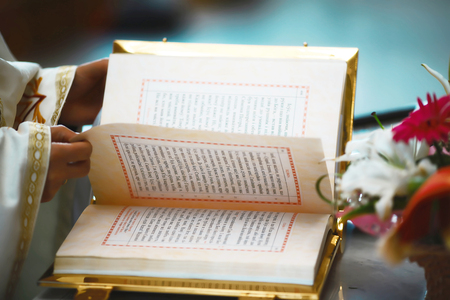 The Book of the Gospel is open for reading in the hands of the priest at the wedding.の写真素材