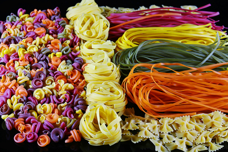 Set of different kinds of colorful Italian pasta, on a black background, healthy food concept, close-up.の写真素材