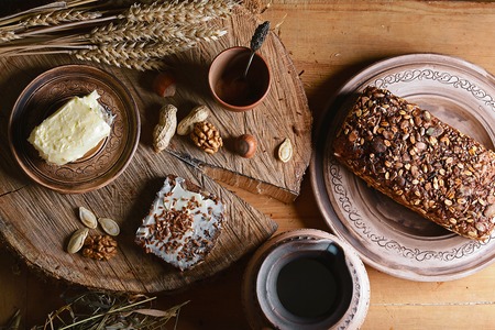 dark cereal bread with sunflower seeds, cup of milk, butter and nuts, concept of healthy eating, on a wooden background on a stump, set.の写真素材