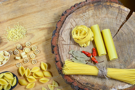 Various mix of pasta on wooden rustic background, spices red pepper, bay leaf, diet and food concept, top view, set.の写真素材