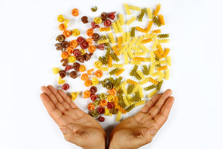 various kinds of colored raw Italian pasta fall in the opening hands on a white background, concept: slim figure in your hands., top view, set.の写真素材