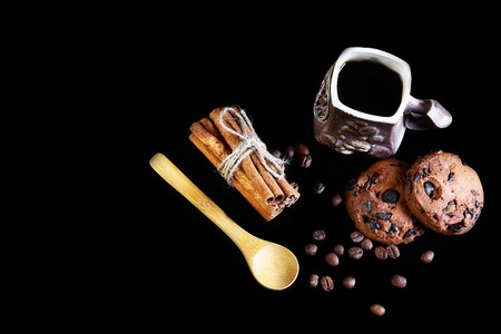 close-up cup of espresso coffee, milk and spoon, round crunchy chocolate cookies with coffee beans, sticks of cinnamon on a black background, macro, empty space for text, top view, set.の写真素材
