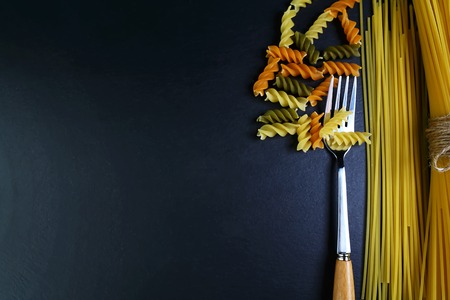 Different kinds of pasta, background of food ingredients on fork, image of the concept of advertising in a restaurant or market, place to copy text, set.の写真素材
