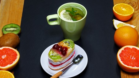 Variety of fruits grapefruit, oranges, kiwi, lemon, mint, cake, sweet fruit dessert bunched, cup of tea together on a shale board, the concept of healthy eating, copy space, top view set.の写真素材