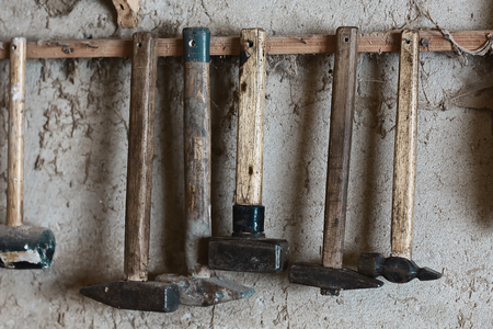 Hammers tools with a wooden handle and a metal tip of retro vintage dirty style, hung on a nail...