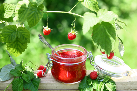 Raspberry jam in a glass jar and fresh raspberry outdoors, selective focus.の写真素材