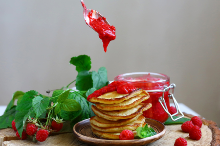 Delicious pancakes with raspberries on the wooden board. raspberry jam poured on pancakes.の写真素材